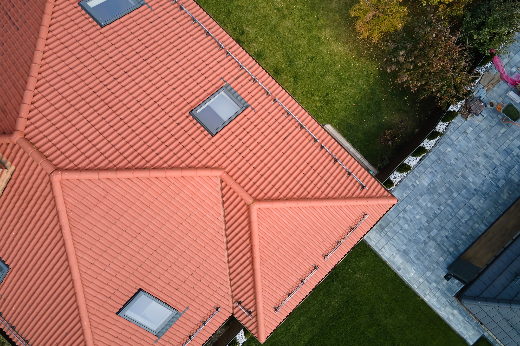 Closeup of attic windows on house roof top covered with ceramic shingles. Tiled covering of building
