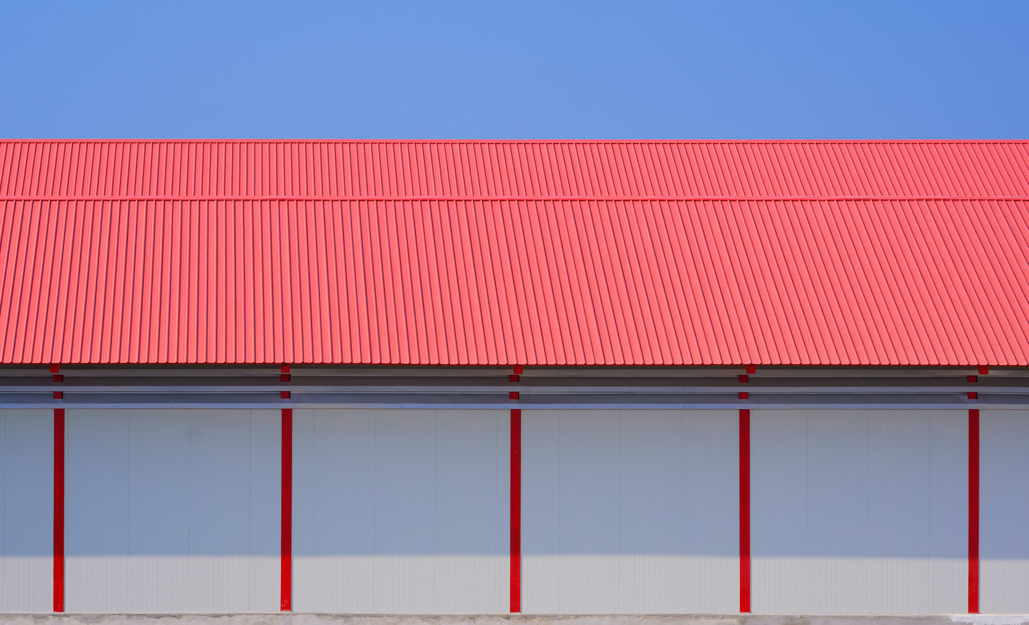 White sandwich panel wall and red metal gable roof of 2 industrial cold storage warehouse buildings