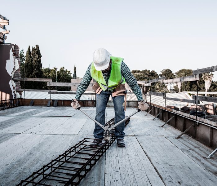 A mason cuts a metal structure with shears in a building under construction.