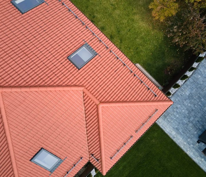 Closeup of attic windows on house roof top covered with ceramic shingles. Tiled covering of building